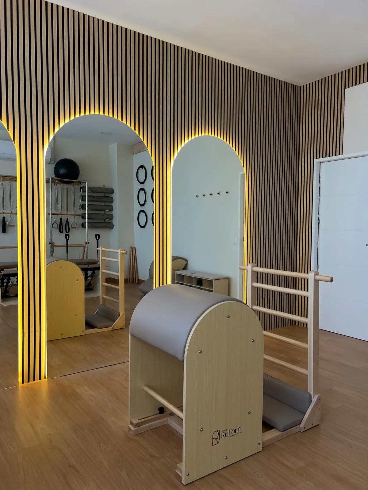 Barril de pilates e espaldar em frente a um espelho em arco