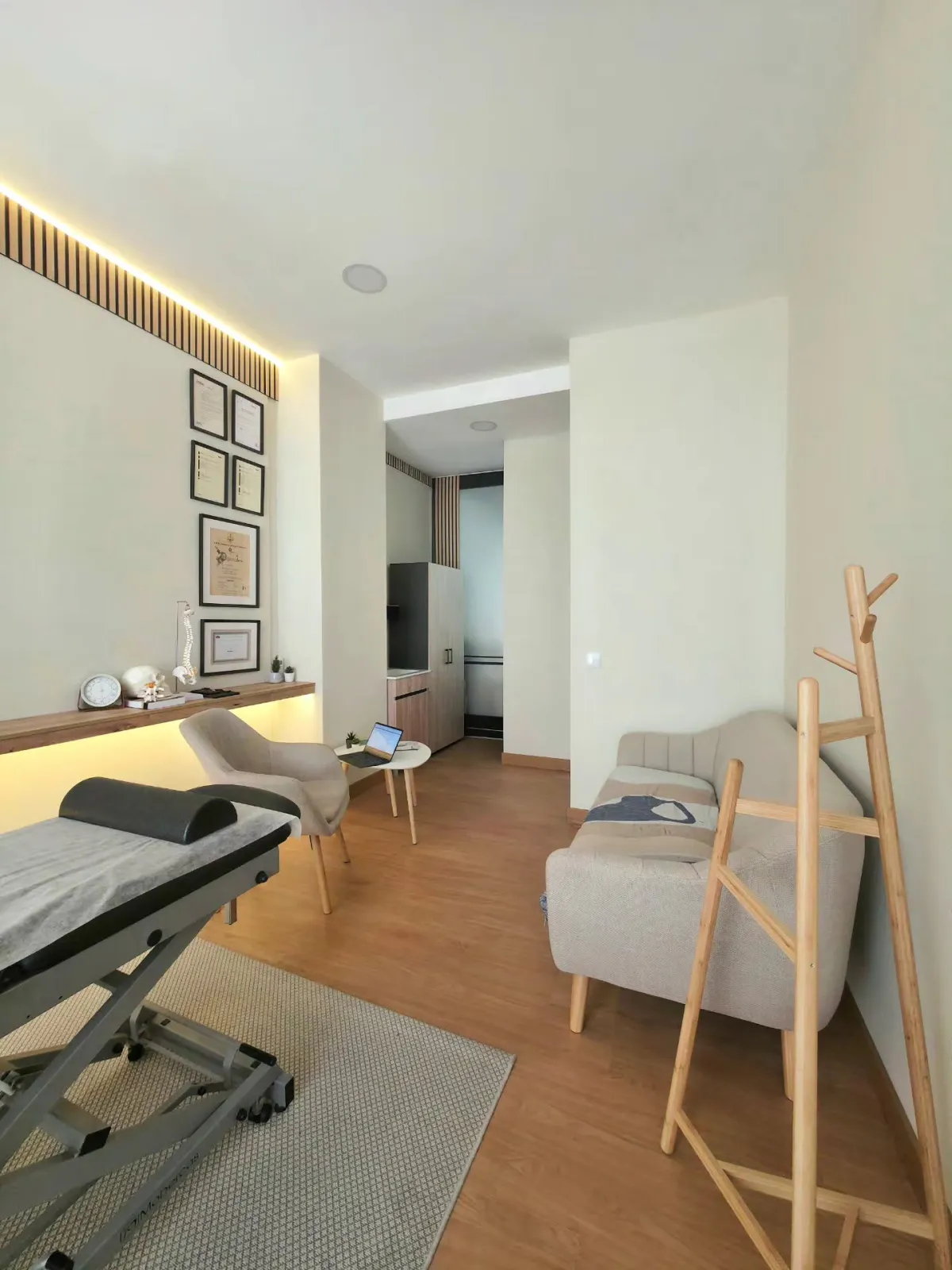 Marquesa de osteopatia junto à janela, com certificados na parede